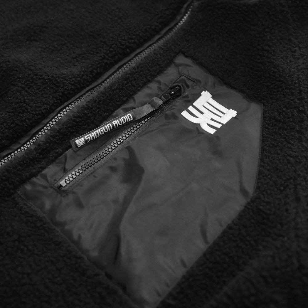 Close-up of a black jacket with a zipper pocket and visible brand logo.